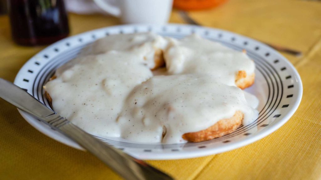 Chicken with creamy gravy on a white plate with fork