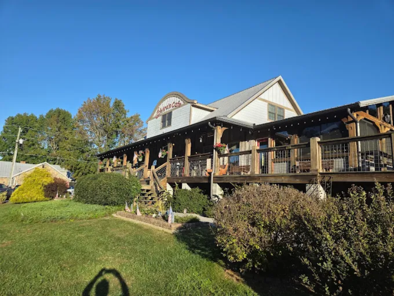 Charming countryside restaurant with porch, stairs, and greenery landscape